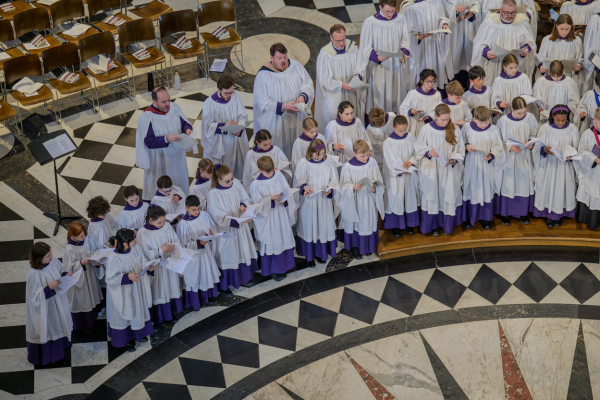 The choir of Durham Cathedral, dressed in white and purple robes.