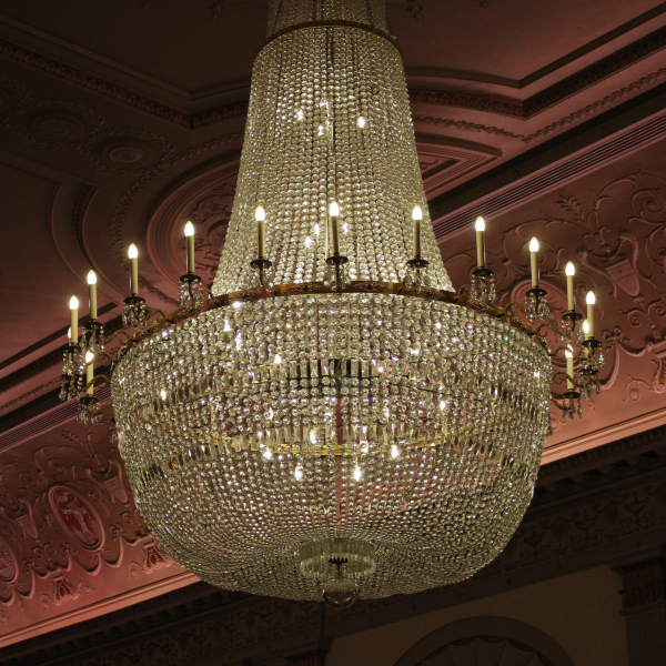 A chandelier, bright against a darkened ceiling.