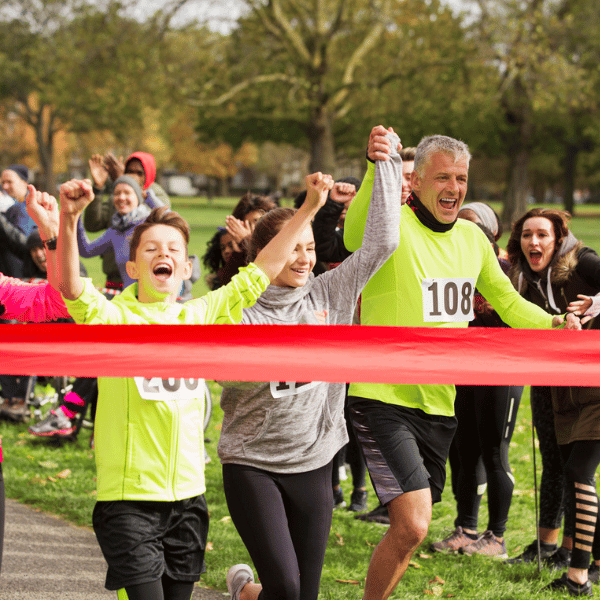 A family in running gear, approaching the Finish Line of a sponsored run.