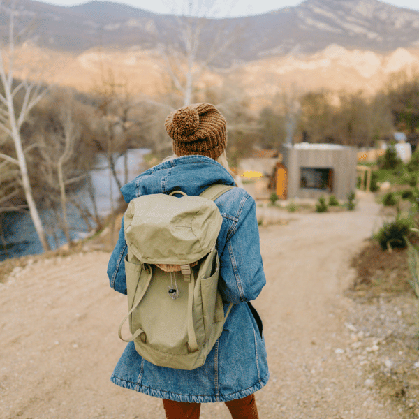 A woman enjoying a hike. She is wearing a brown bobble hat, and a blue jacket.