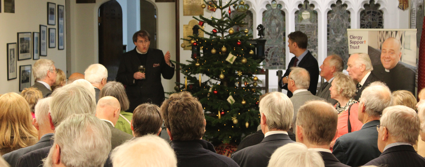 The Revd Ben Cahill-Nicholls, giving a speech to guests, beside a Christmas tree.