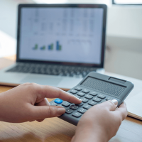 A calculator, and a laptop showing spreadsheets.